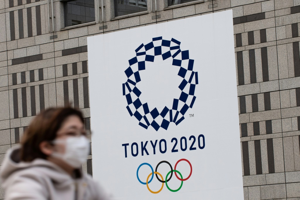 Une femme portant un masque passe devant le logo des Jeux olympiques de Tokyo