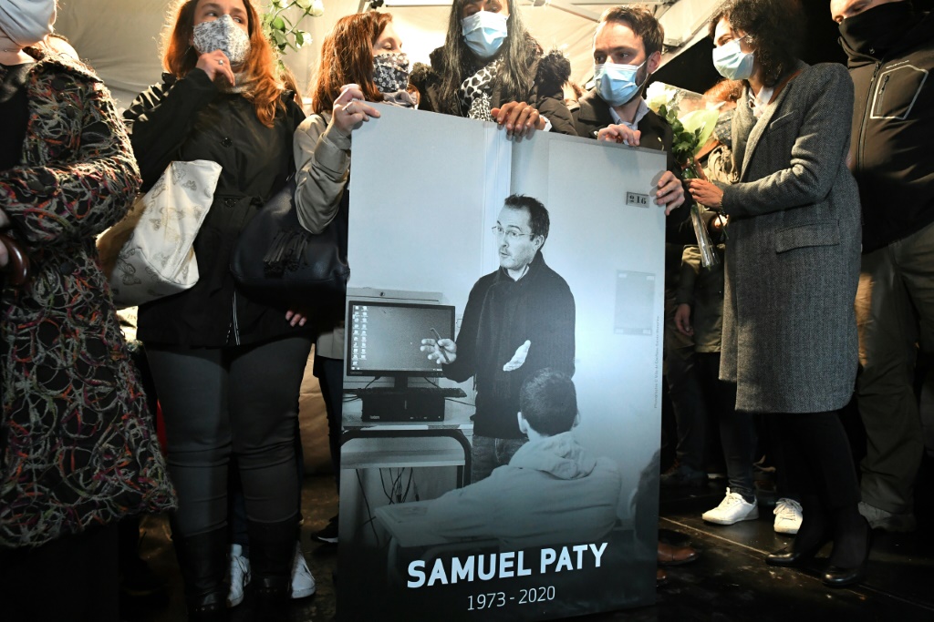 Des parents et des collègues tiennent une photo de Samuel Paty lors de la marche blanche à Conflans-Sainte-Honorine