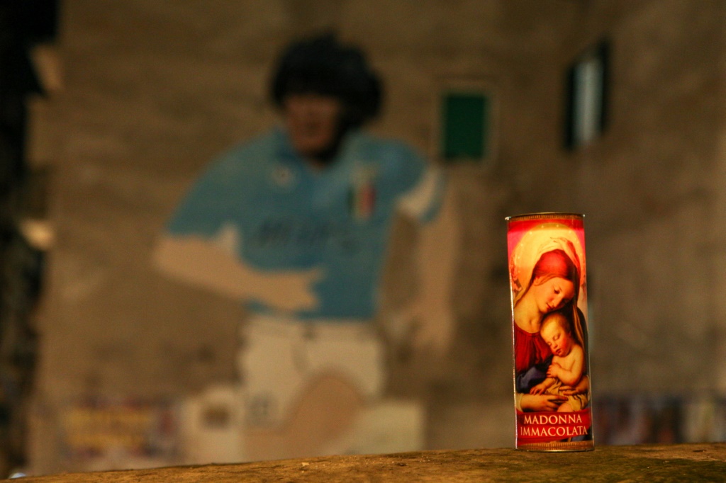 Une bougie de la Vierge devant une fresque de Diego Maradona à Naples