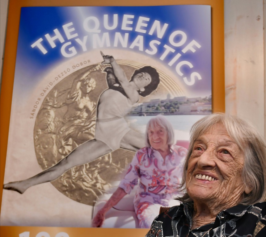 La championne olympique hongroise Agnes Keleti devant une affiche de sa biographie