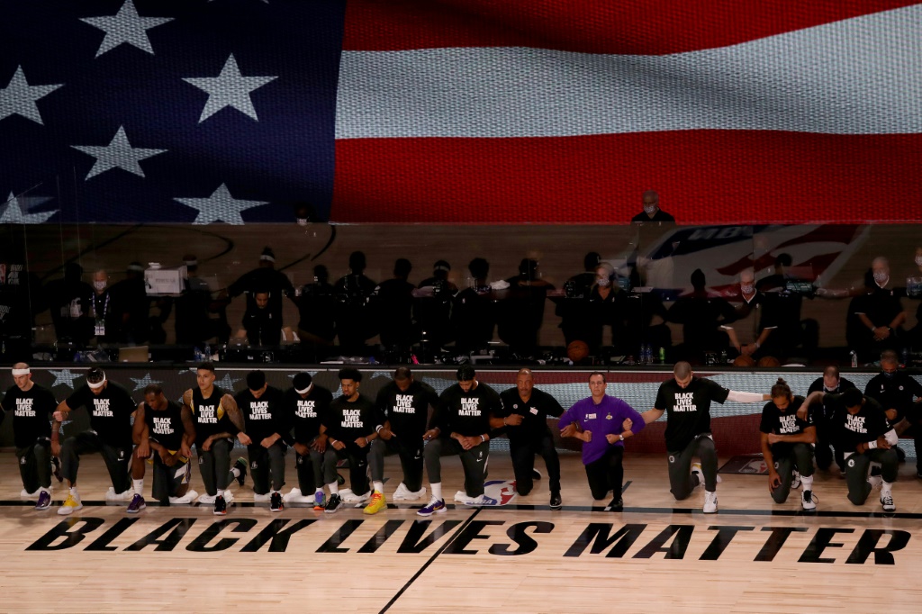 Membres des Los Angeles Lakers et des LA Clippers agenouillés devant le mot d'ordre "Black lives matter" et durant l'hymne américain avant leur match de NBA