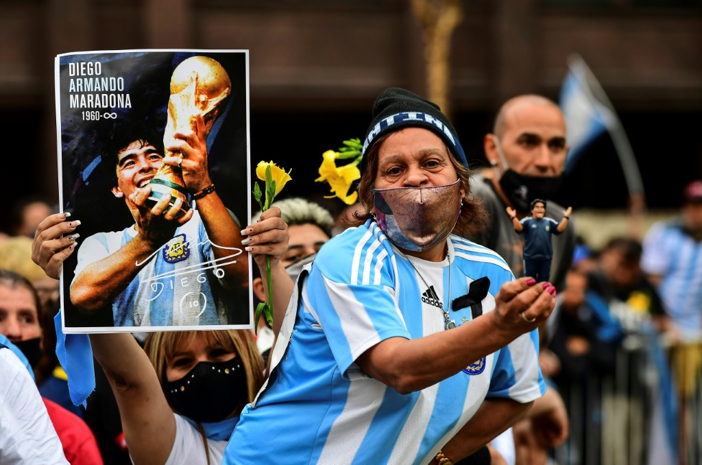 Des fans de Maradona avec un portrait et une figurine du légendaire numéro 10