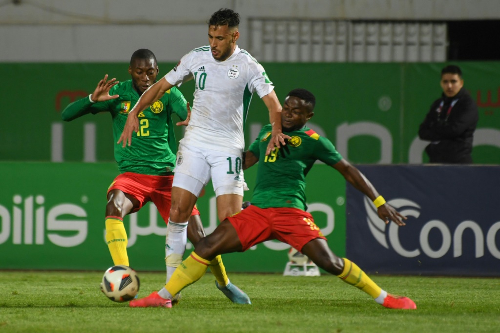 Le milieu de terrain algérien Sofiane Feghouli (C) dispute le ballon à l'attaquant camerounais Karl Toko Ekambi et au défenseur camerounais Collins Fai lors du match retour des éliminatoires de la Coupe du monde de football du Qatar 2022 entre l'Algérie et le Cameroun au stade de Blida