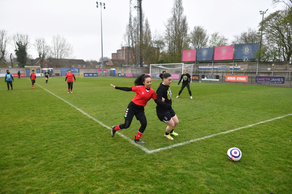 Une joueuse afghane de l'équipe nationale espoirs, aux prises avec une députée britannique, le 29 mars 2022 dans le stade de Dulwich Hamlet FC au sud de Londres, lors d'une rencontre organisée par Amnesty International