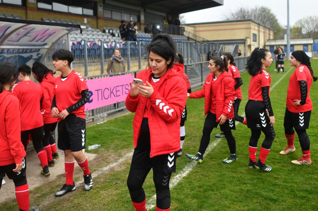 Une joueuse afghane de l'équipe nationale espoirs consulte son téléphone à la mi-temps du match contre des députées britanniques, le 29 mars 2022 dans le stade de Dulwich Hamlet FC au sud de Londres, lors d'une rencontre organisée par Amnesty International