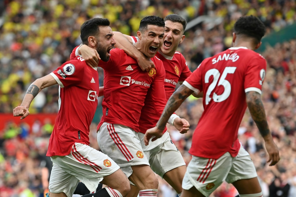 La joie du Portugais Cristiano Ronaldo (2e g), félicité par ses coéquipiers, après avoir marqué les 3 buts de la victoire à domicile de Manchester United, 3-2 face à Norwich, lors de la 33e journée de Premier League, le 16 avril 2022 au Stade d'Old Trafford