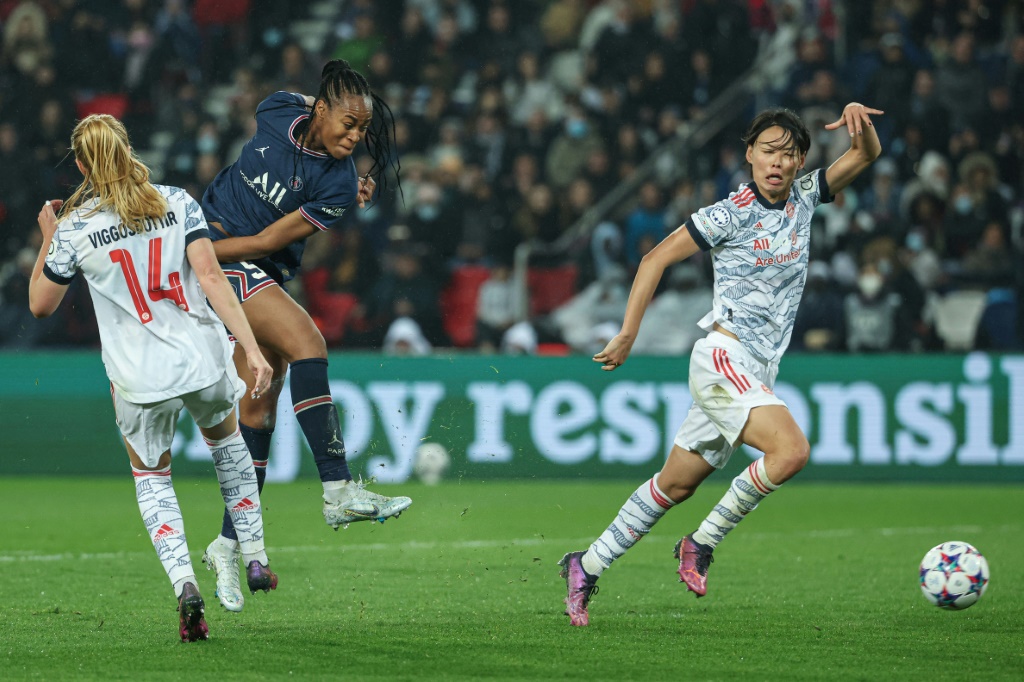 L'attaquante du Paris Saint-Germain Marie-Antoinette Katoto tire au but sous le regard de la milieu de terrain japonaise du Bayern Munich Saki Kumagai, lors du quart de finale retour de la Ligue des Champions, le 30 mars 2022 au Parc des Princes