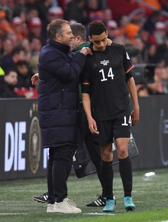 Germany's coach Hans-Dieter Flick talks to Germany's forward Jamal Musiala (R) during the friendly football match between The Netherlands and Germany at the Johan Cruijff ArenA in Amsterdam on March 29, 2022.