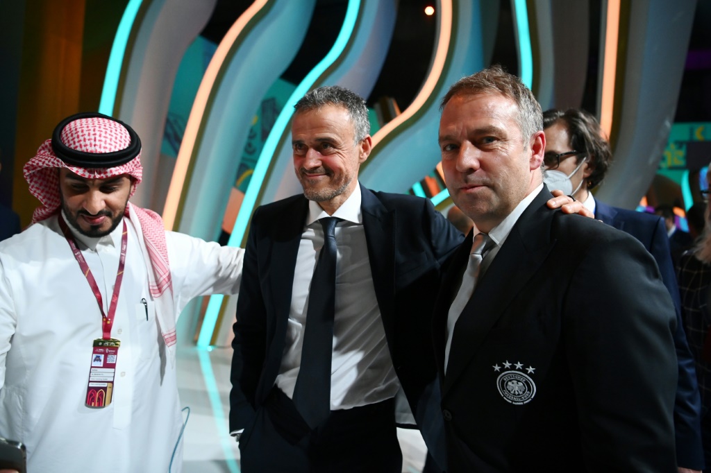 Le sélectionneur de l'Espagne Luis Enrique (au centre) avec son homologue de l'Allemagne Hansi Flick à l'issue du tirage au sort du Mondial à Doha, le 1er avril 2022