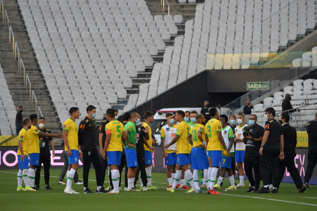 Les joueurs brésiliens et leurs rivaux argentins regroupés sur la pelouse après l'intervention des agents des services sanitaires pour violation du protocole anticovid