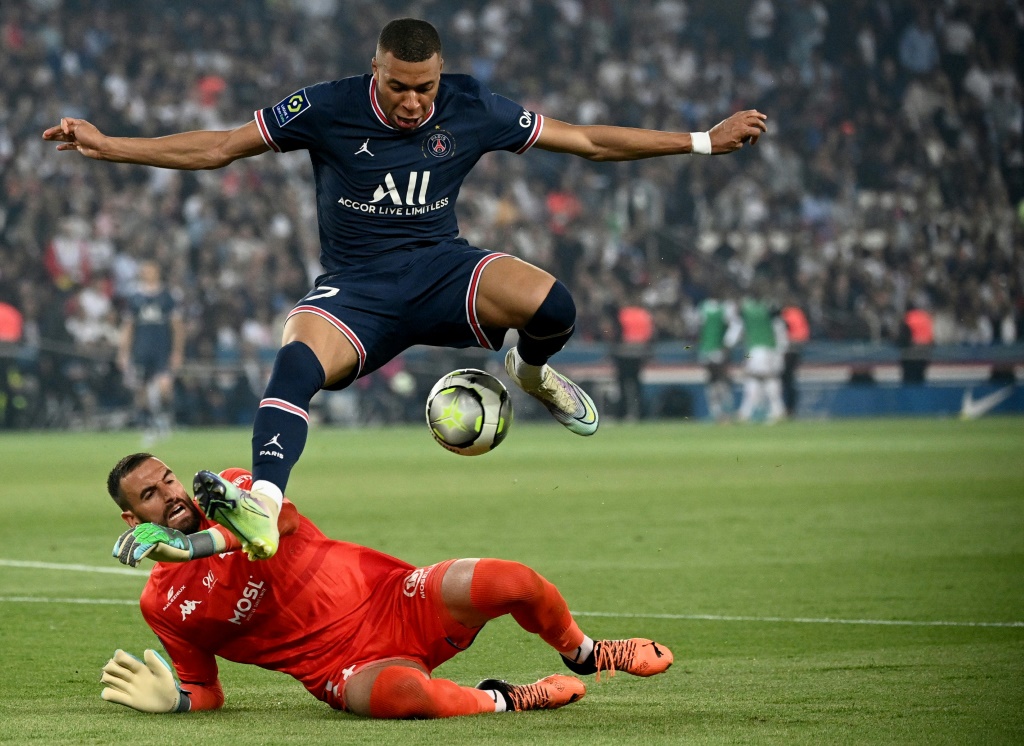 L'attaquant du Paris Saint-Germain Kylian Mbappé saute au-dessus du gardien de Metz Marc-Aurèle Caillard durant la rencontre entre les deux clubs le 21 mai 2022 au Parc des Princes à Paris