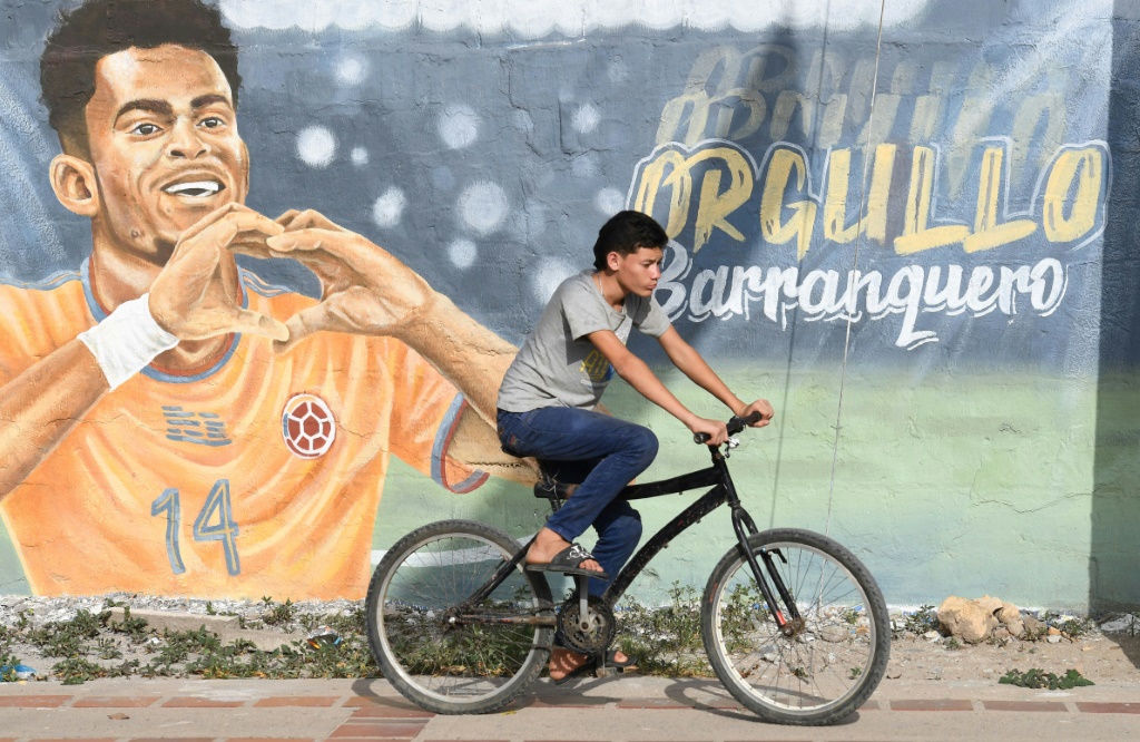 Un cycliste passe devant une fresque de Luis Diaz, le 22 mai 2022 à Barrancas, où est né l'attaquant colombien de Liverpool qui jouera la finale de la Ligue des Champions contre le Real Madrid, le 28 mai 2022 au Stade de France à Saint-Denis