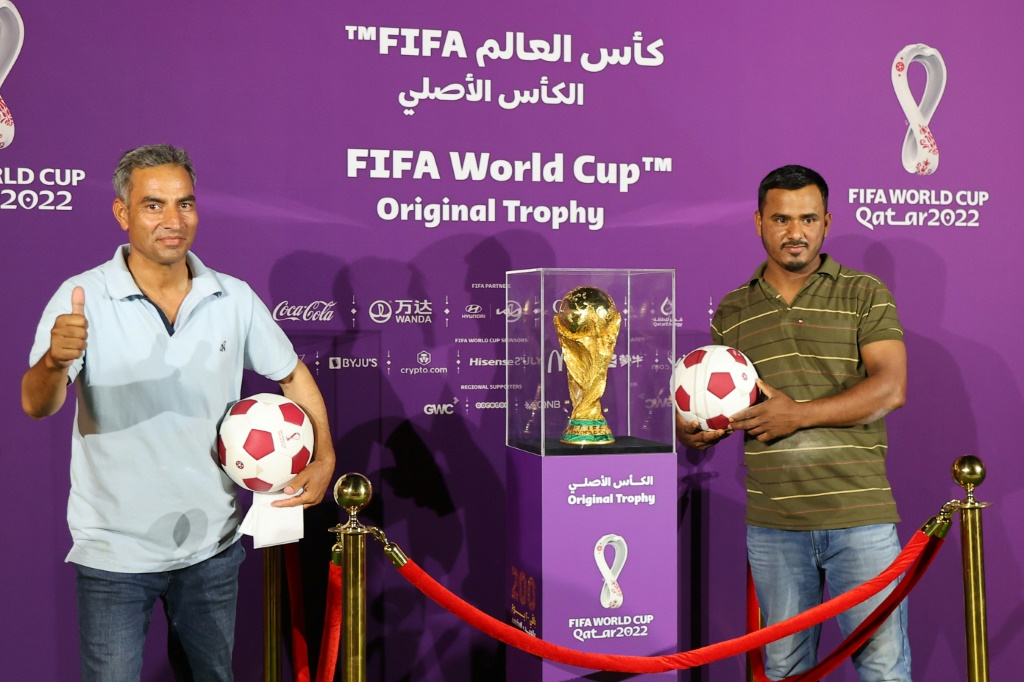 Deux personnes posent devant le Trophée de la Coupe du monde exposé au Qatar, pays organisateur de la prochaine édition, le 6 mai 2022 à Doha