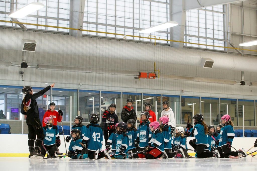 De jeunes Canadiennes suivent des instructions de leur formateur dans la salle de l'Association de hockey de Toronto