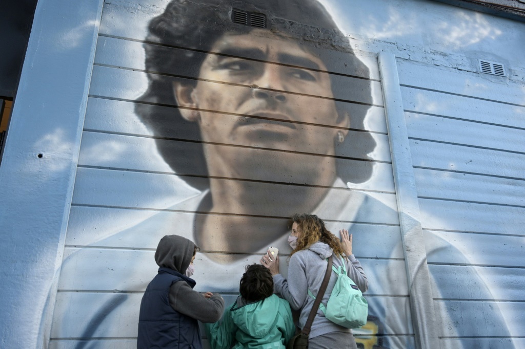 Des personnes se recueillent devant une fresque murale de Diego Maradona
