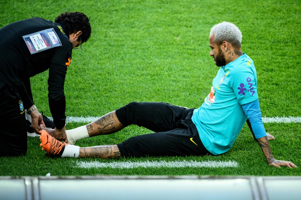 Un médecin de l'équipe nationale brésilienne (gauche) observe le pied de l'attaquant Neymar (droite) lors d'un entraînement de la Seleçao le 1er juin à Séoul, la veille d'une rencontre amicale contre la Corée du Sud