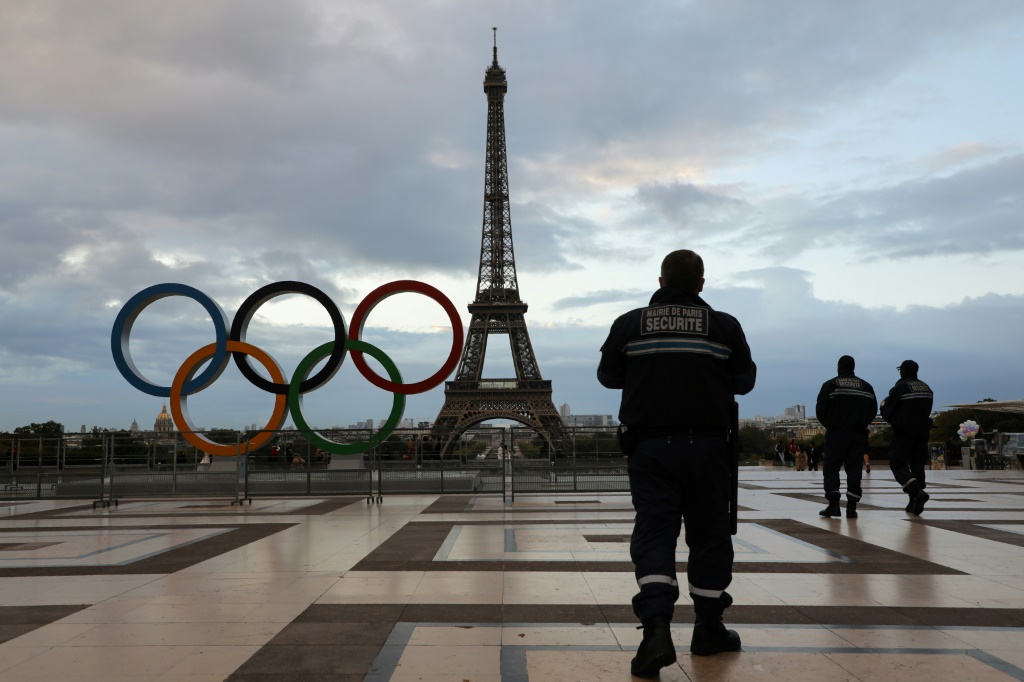 Des agents de sécurité, effectuent une patrouille devant les anneaux olympiques installés près de la Tour Eiffel, le 14 septembre 2017, au lendemain de la désignation officielle de la capitale comme ville-hôte des Jeux de 2024