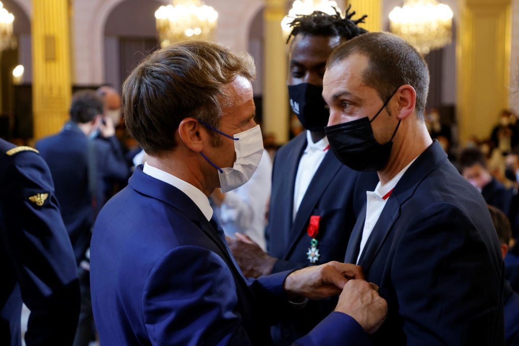 Le handballeur Michaël Guigou décoré de la Légion d'honneur par le président Emmanuel Macron, sous le regard de Luc Abalo, au palais de l'Elysée, le 13 septembre 2021
