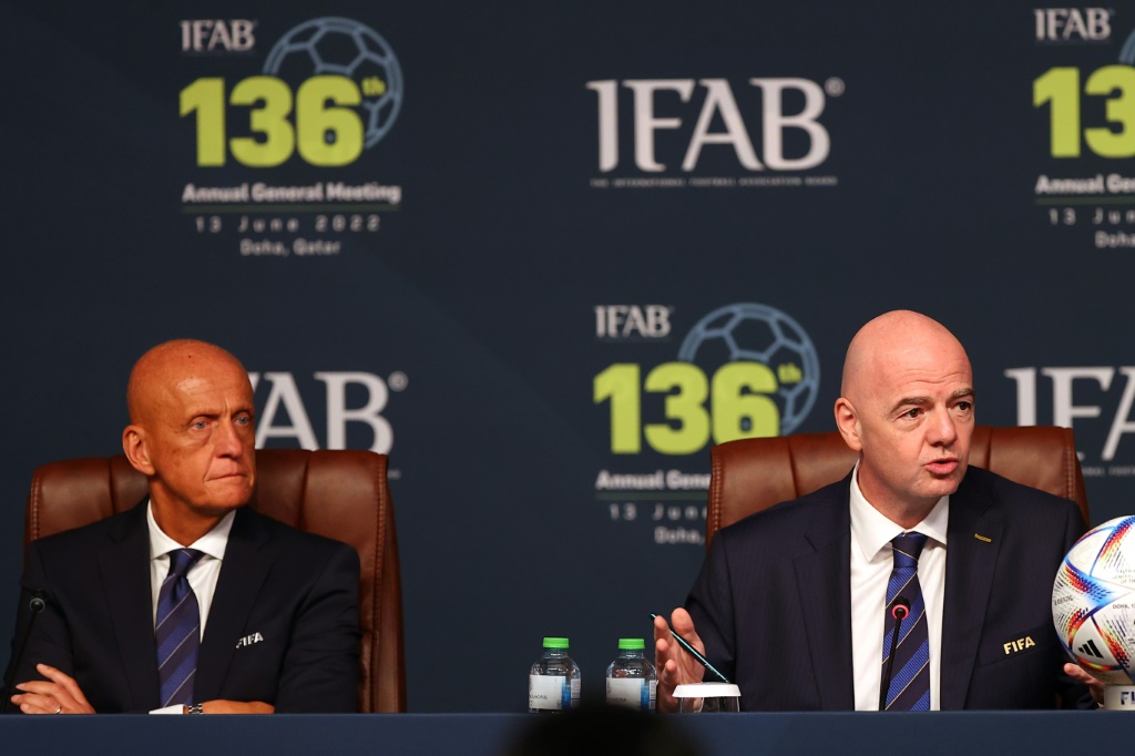 Le président de la FIFA Gianni Infantino s'exprime lors de la 136e assemblée générale annuelle de l'Ifab (International Board), le 13 juin 2022 à Doha, au côté de l'Italien Pierluigi Collina, président de la Commission des Arbitres de la Fifa