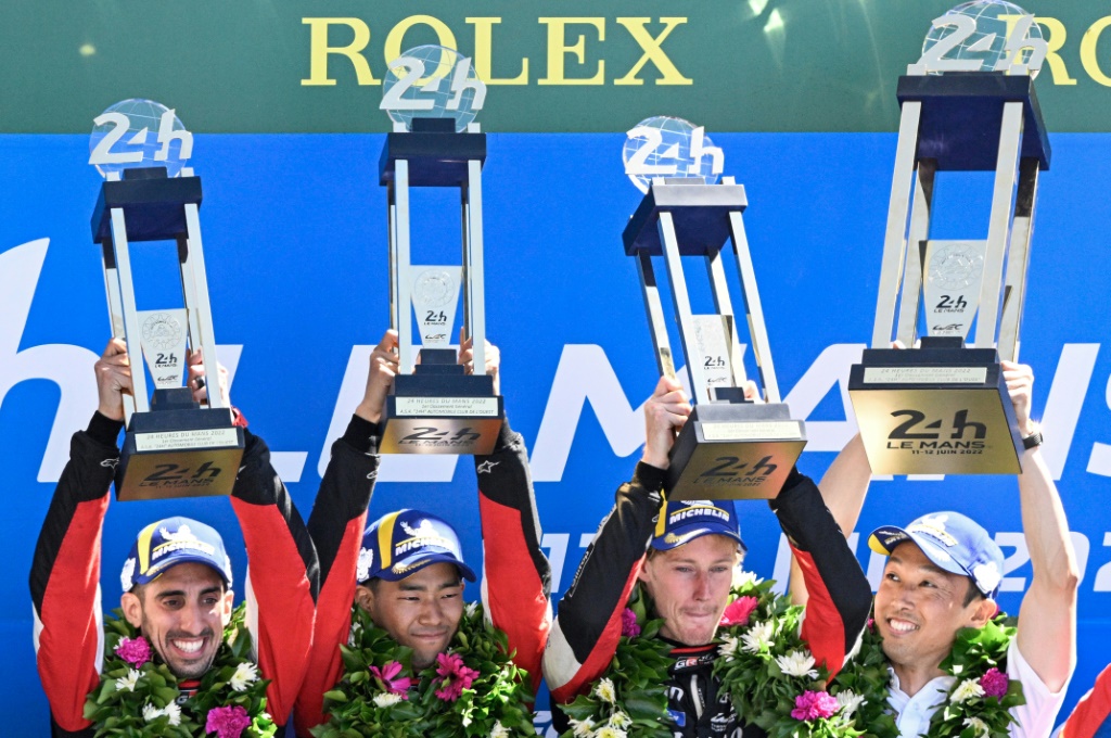 La joie des pilotes de la Toyota N.8, le Suisse Sébastien Buemi (g), le Japonais Ryo Hirakawa (c) et le Néo-Zélandais Brendon Hartley, vainqueurs des 24h du Mans, le 12 juin 2022, au côté du vice-président de Toyota Gazoo Racing, le Japonais Kazuki Nakajima