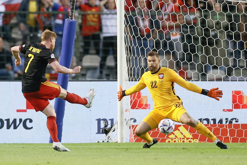 Le milieu de terrain belge Kevin De Bruyne marque le 2e but face au gardien polonais Bartlomiej Dragowski, lors de leur match de Ligue des nations, le 8 juin 2022 à Bruxelles
