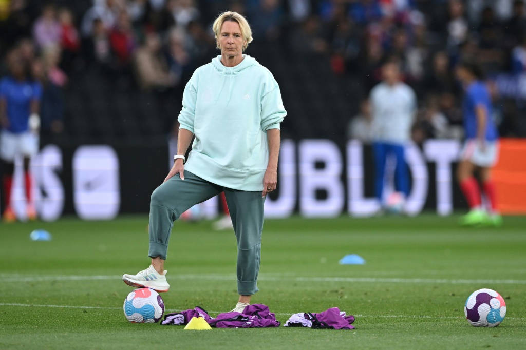 La sélectionneuse allemande Martina Voss-Tecklenburg supervise l'échauffement de ses joueuses avant la demi-finale de l'Euro contre la France à Milton Keynes, le 27 juillet 2022