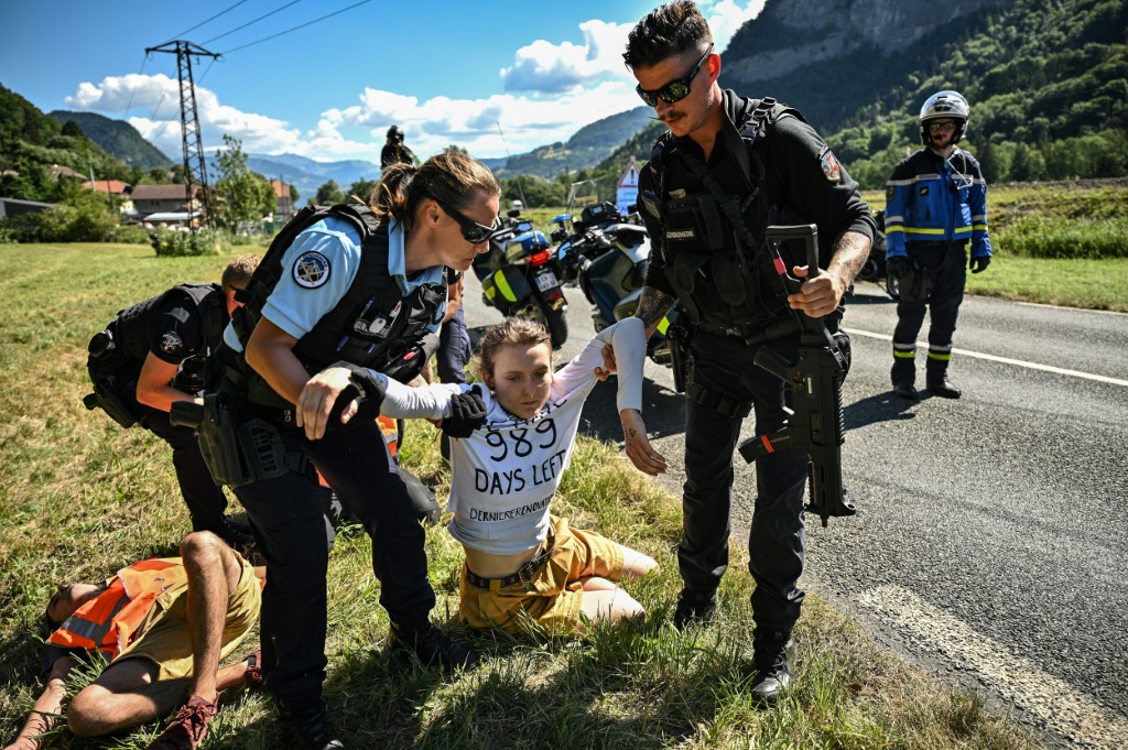 Des gendarmes évacuent des militants environnementaux le 12 juillet 2022 sur le tracé de la 10e étape du Tour de France. La réalité, c’est que le monde vers lequel nous envoient les politiques est un monde dans lequel le Tour de France ne pourra plus exister, a commenté une militante du groupe Dernière rénovation qui a revendiqué l'opération