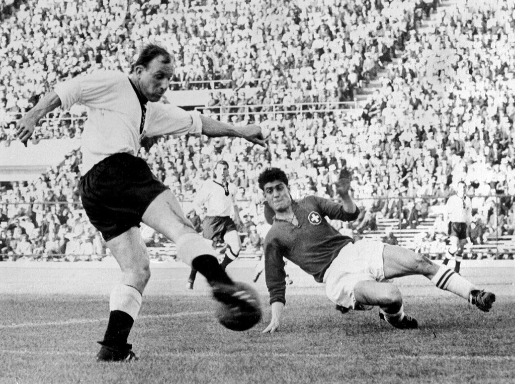L'attaquant allemand Uwe Seeler tire au but malgré le retour du défenseur suisse Heinz Schneiter, lors de leur match du 1er tour de la Coupe du monde, le 3 juin 1962 à Santiago (Chili)