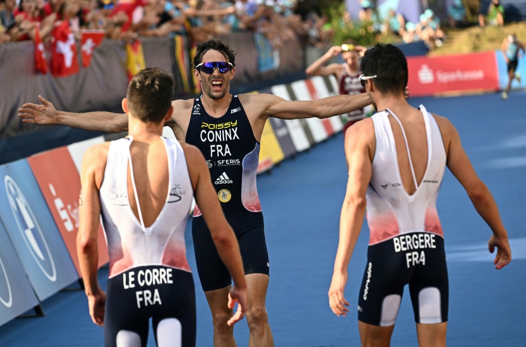 Le Français Dorian Coninx (c.) célèbre sa médaille de bronze avec ses compatriotes Leo Bergere (d.), médaillé d'or, et Pierre Le Corre (g.), médaillé d'argent, à l'issue de l'épreuve de triathlon masculin au Parc olympique de Munich, le 13 août 2022