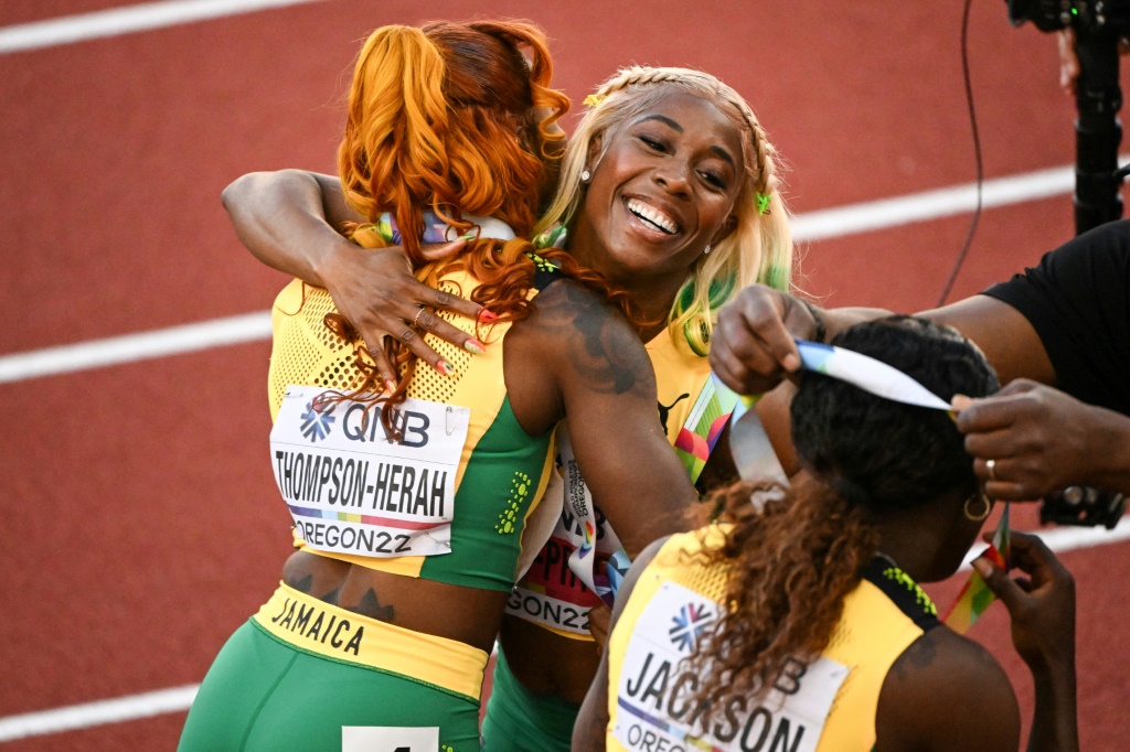 La championne du monde jamaïcaine Shelly-Ann Fraser-Pryce (c.) étreint sa compatriote, la médaillée de bronze Elaine Thompson-Herah (g.), avec Shericka Jackson (d.), vice-championne du monde, le 17 juillet à Eugene (Etats-Unis)