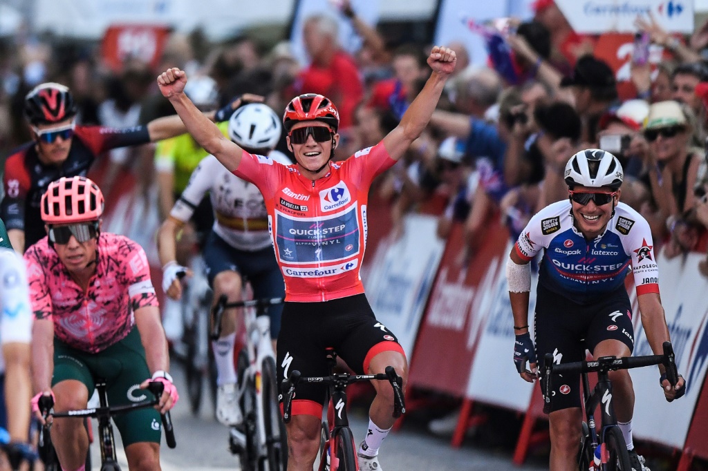 Remco Evenepoel lève les bras à l'arrivée de la 21e et dernière étape de la Vuelta, le 11 septembre 2022 à Madrid. A 22 ans seulement, il est le premier Belge à remporter un grand Tour depuis Johan de Muynck en 1978 sur le Giro