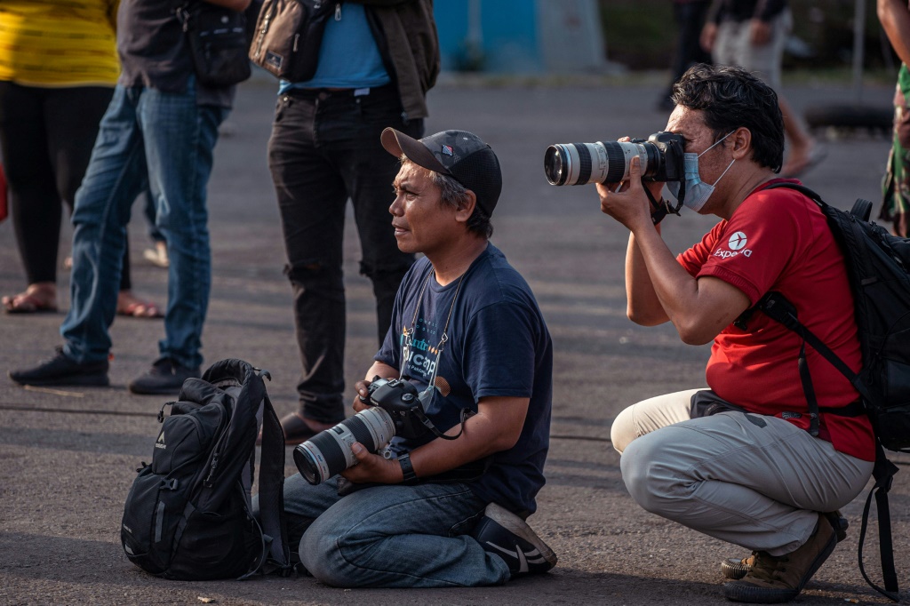 Le photographe Adi Bowo Sucipto (G) au travail après la bousculade meurtrière au stade de la ville de Malang en Indonésie, le 4 octobre 2022