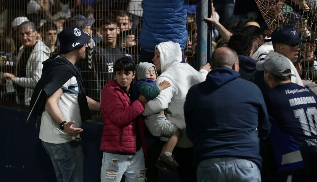 Des supporteurs tentent de s'éloigner des gaz lacrymogènes pendant des incidents au stade de La Plata, près de Buenos Aires, le 6 octobre 2022