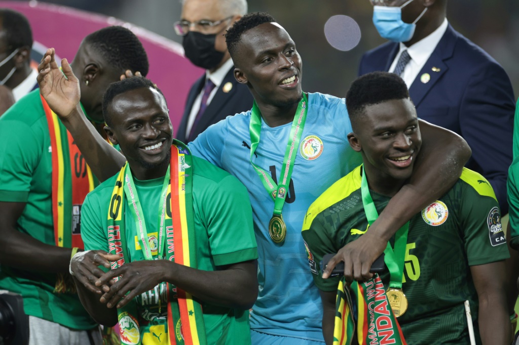 Le gardien du Sénégal Edouard Mendy entouré de ses coéquipiers Sadio Mané (g) et Bamba Dieng, après avoir remporté la finale de Coupe d'Afrique des nations contre l'Egypte, le 6 février 2022 à Yaoundé