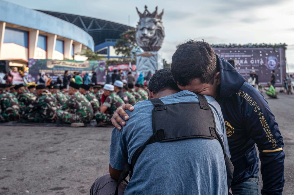 Des soldats de l'armée indonésienne et des civils rendent hommage aux victimes de la bousculade au stade de Kanjuruhan à Malang (Indonésie), dans l'est de Java, le 4 octobre 2022