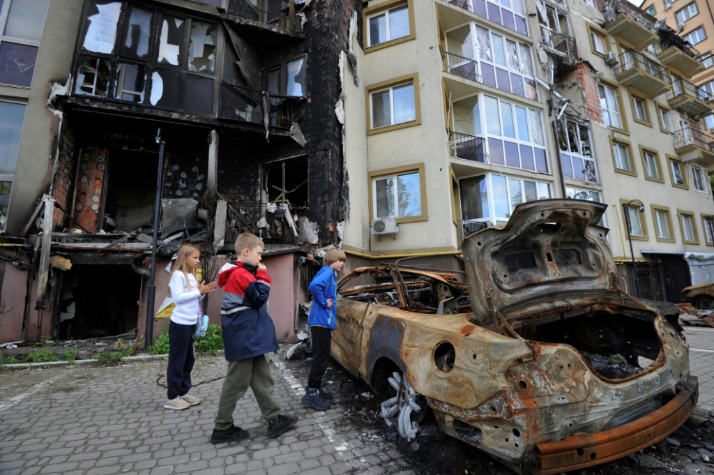 Des enfants ukrainiens jouent au pied d'un immeuble détruit à Irpin, le 11 septembre 2022