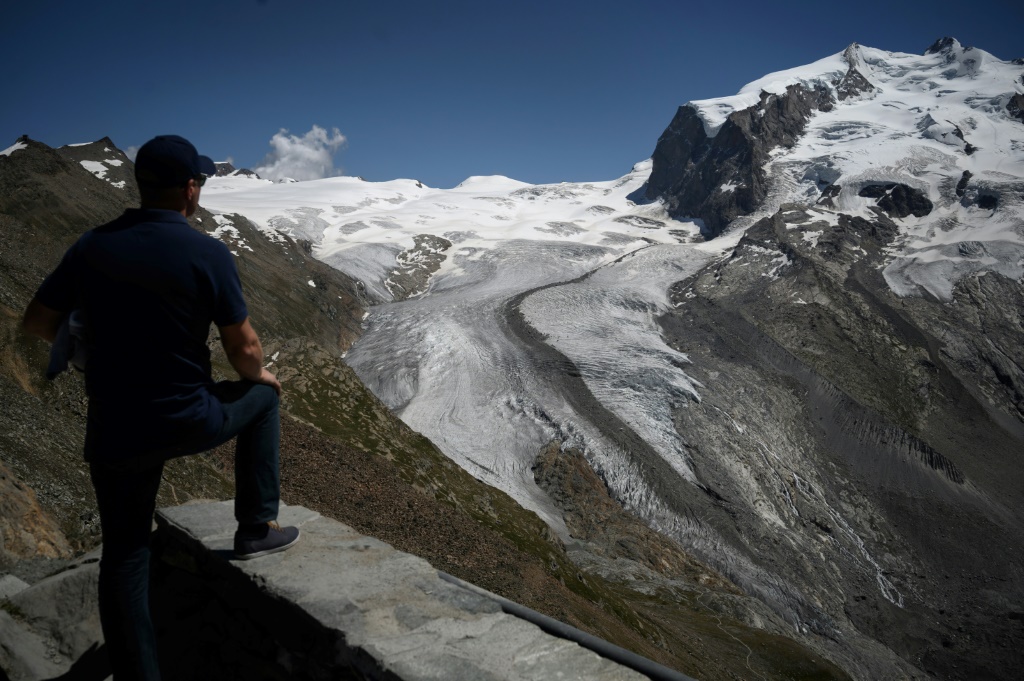 Un touriste regarde le glacier du Gorner en train de fondre, à 3089 mètres d'altitude au-dessus de la station de Zermatt, en Suisse, le 8 août 2020