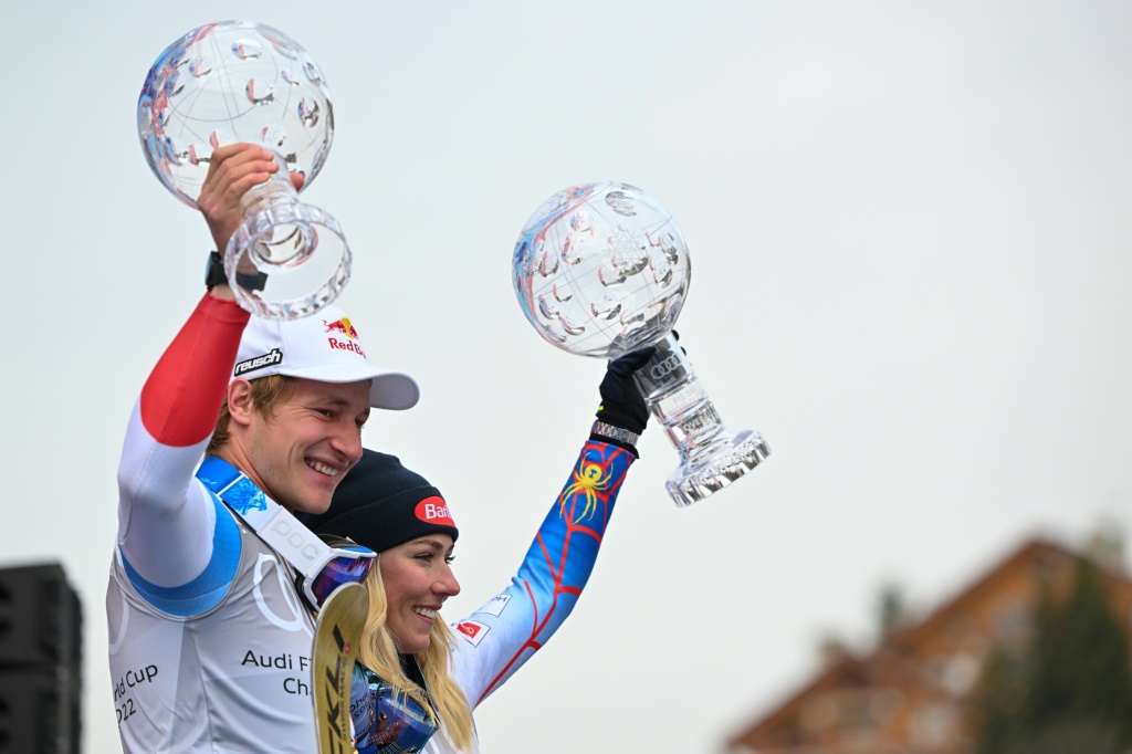 Le Suisse Marco Odermatt (G) et l'Américaine Mikaela Shiffrin brandissent le globe de cristal sur le podium lors des finales de la Coupe du monde de ski alpin FIS 2021/2022 à Méribel, dans les Alpes françaises, le 20 mars 2022