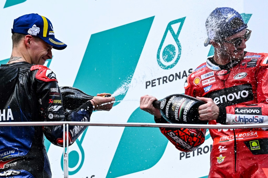 Le pilote Ducati Pecco Bagnaia et Fabio El Diablo Quartararo, son rival de Yamaha pour le sacre, s'arrosent de champagne sur le podium du GP moto de Malaisie à Sepang, le 23 octobre 2022