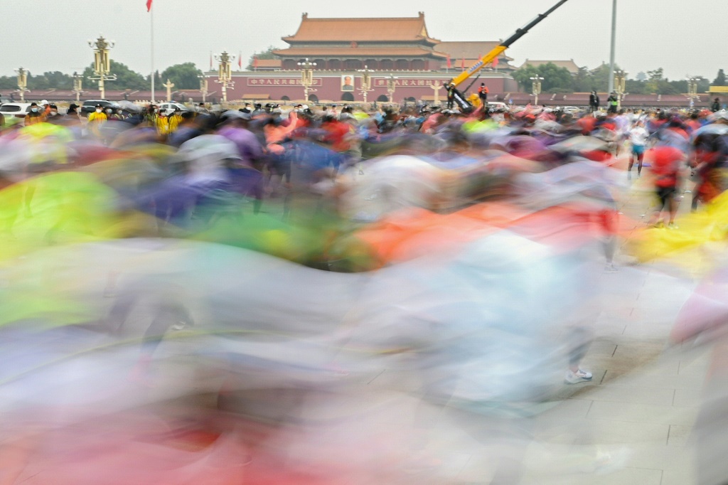 Photo en exposition longue des participants au marathon de Pékin passant sur la place Tiananmen