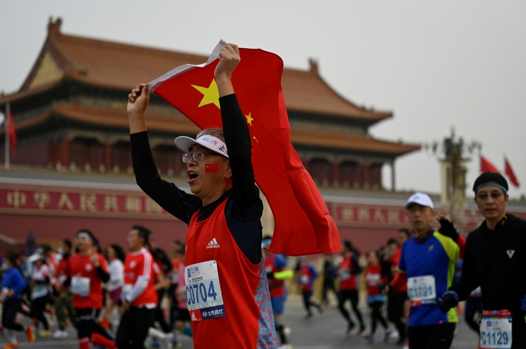 Un des participants au marathon de Pékin brandit un drapeau chinois, le 6 novembre 2022
