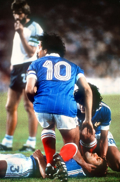 Michel Platini (N.10) et Didier Six au chevet de Patrick Battiston le 8 juillet 1982 après le choc entre le défenseur français et le gardien allemand Harald Shumacher en demi-finale de la Coupe du monde à Séville