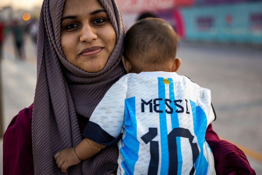 Une supportrice de l'Argentine et son enfant portant un maillot floqué Messi, sur le front de mer à Doha, le 11 novembre 2022, à quelques jours du début de la Coupe du monde
