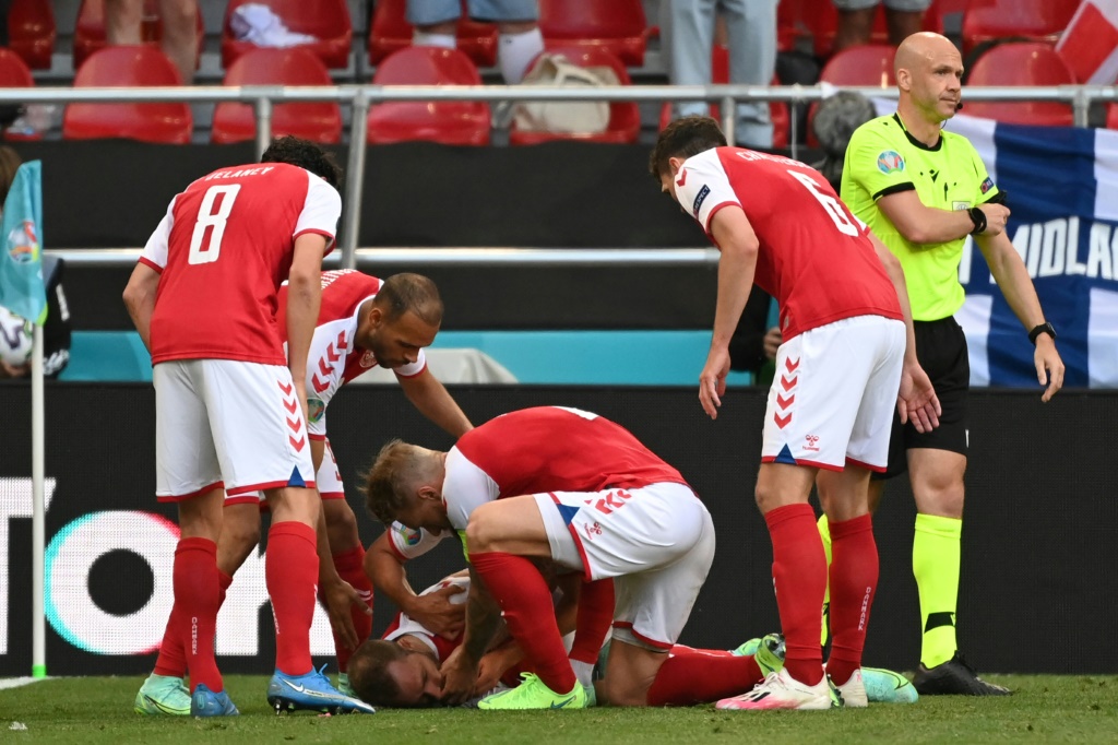 Les joueurs danois aident le milieu de terrain Christian Eriksen, qui vient de faire un malaise, avant l’arrivée des médecins lors du match entre le Danemark et la Finlande à Copenhague le 12 juin 2021