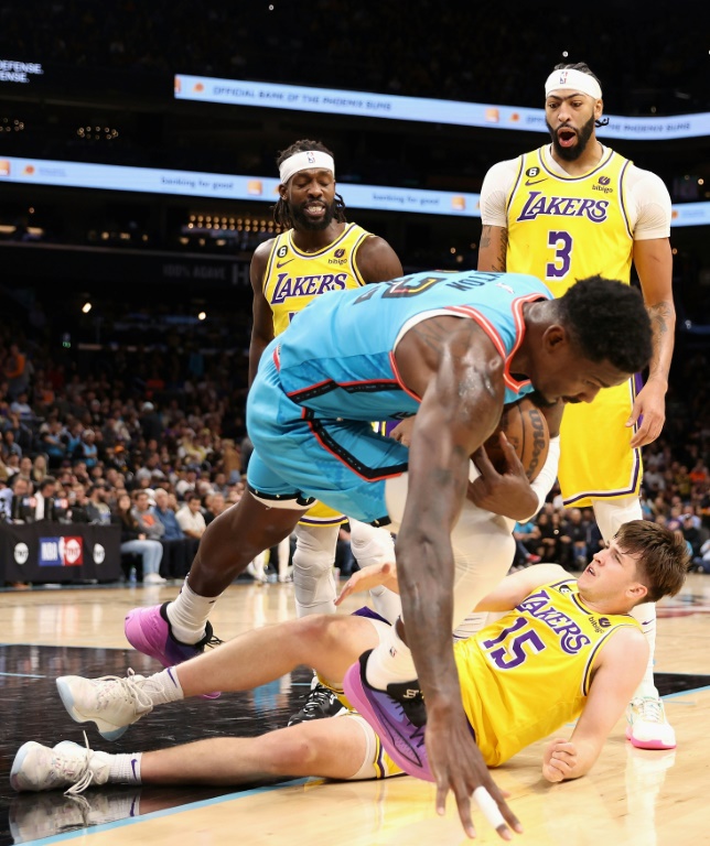 Patrick Beverley, des Los Angeles Lakers pousse Deandre Ayton (c.) des Phoenix Suns par-dessus Austin Reaves pendant la deuxième mi-temps du match NBA entre les Lakers et les Suns, à Phoenix, le 22 novembre 2022