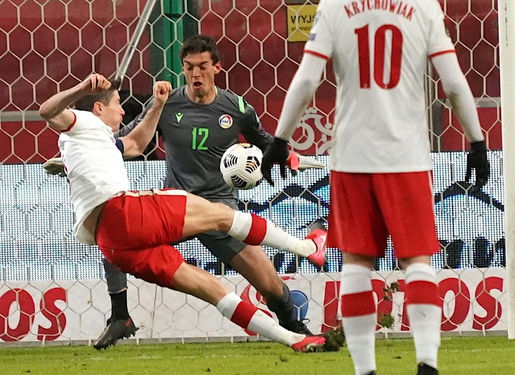 L'attaquant polonais Robert Lewandowski (g) trompe le gardien andorran Iker lors du match de qualification pour la Coupe du monde 2022, à Varsovie, le 28 mars 2021