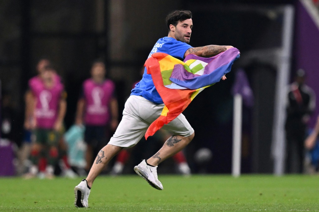 Un homme s'infiltre sur le terrain avec un drapeau LGBT+ durant le match Portugal-Uruguay au Stade de Lusail à Doha, le 28 novembre 2022