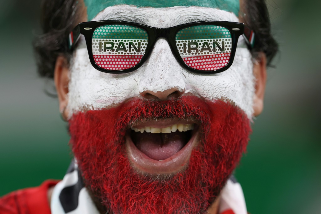 Un supporter iranien souriant au moment du coup d'envoi du match du Mondial entre l'Iran et les Etats-Unis au stade al-Thumama le 29 novembre 2022 à Doha