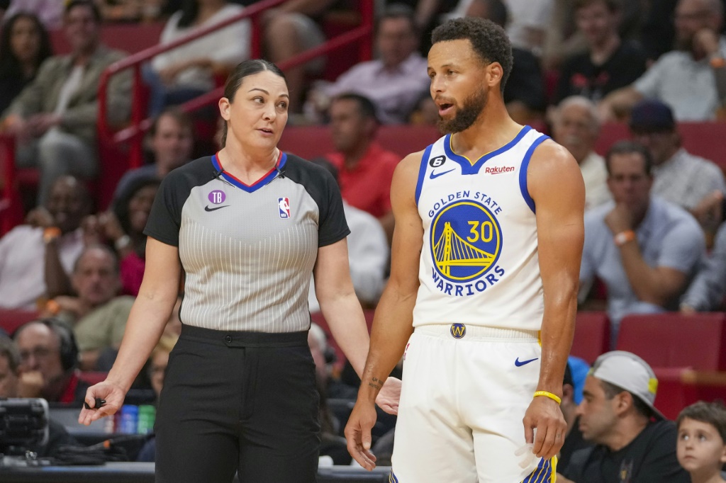 Stephen Curry (d.), des Golden State Warriors, discute avec l'arbitre Lauren Holtkamp-Sterling (g.) pendant le match de NBA contre le Miami Heat, à Miami, le 1er novembre 2022