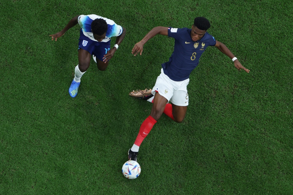 Le milieu de terrain de la France Aurélien Tchouameni (c.) devant l'attaquant de l'Angleterre Bukayo Saka (g.) pendant le quart de finale de la Coupe du monde 2022 entre l'Angleterre et la France